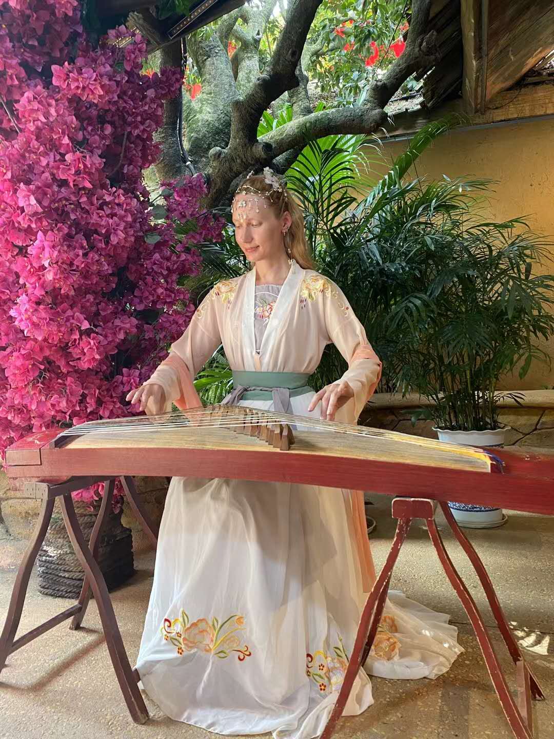 Rebecca wearing traditional-style clothing beside a Chinese stringed instrument
