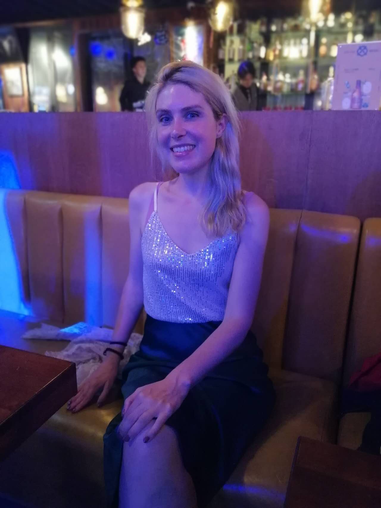 Rebecca seated in a venue under blue lighting