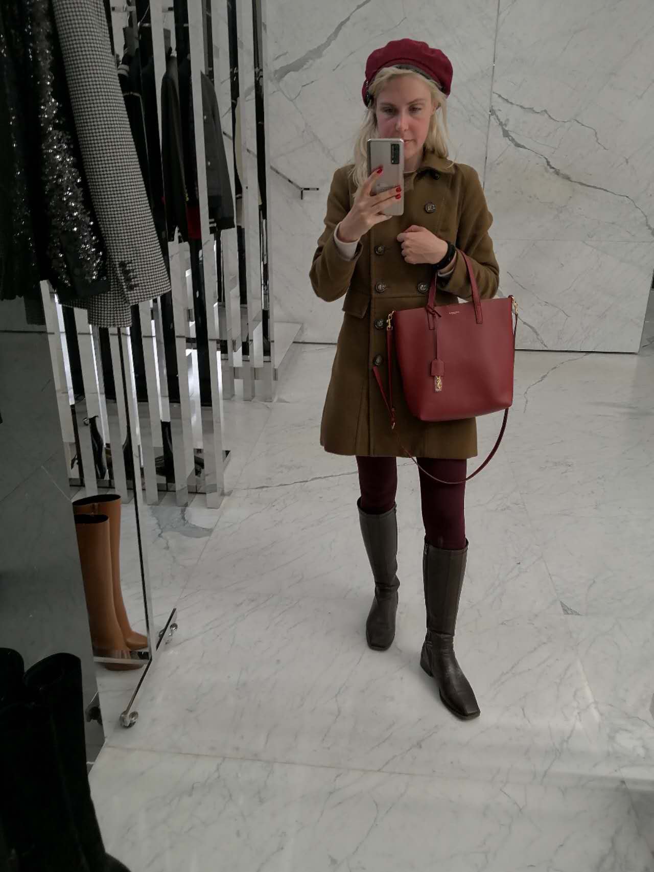 Rebecca wearing a coat and red beret in a shop mirror