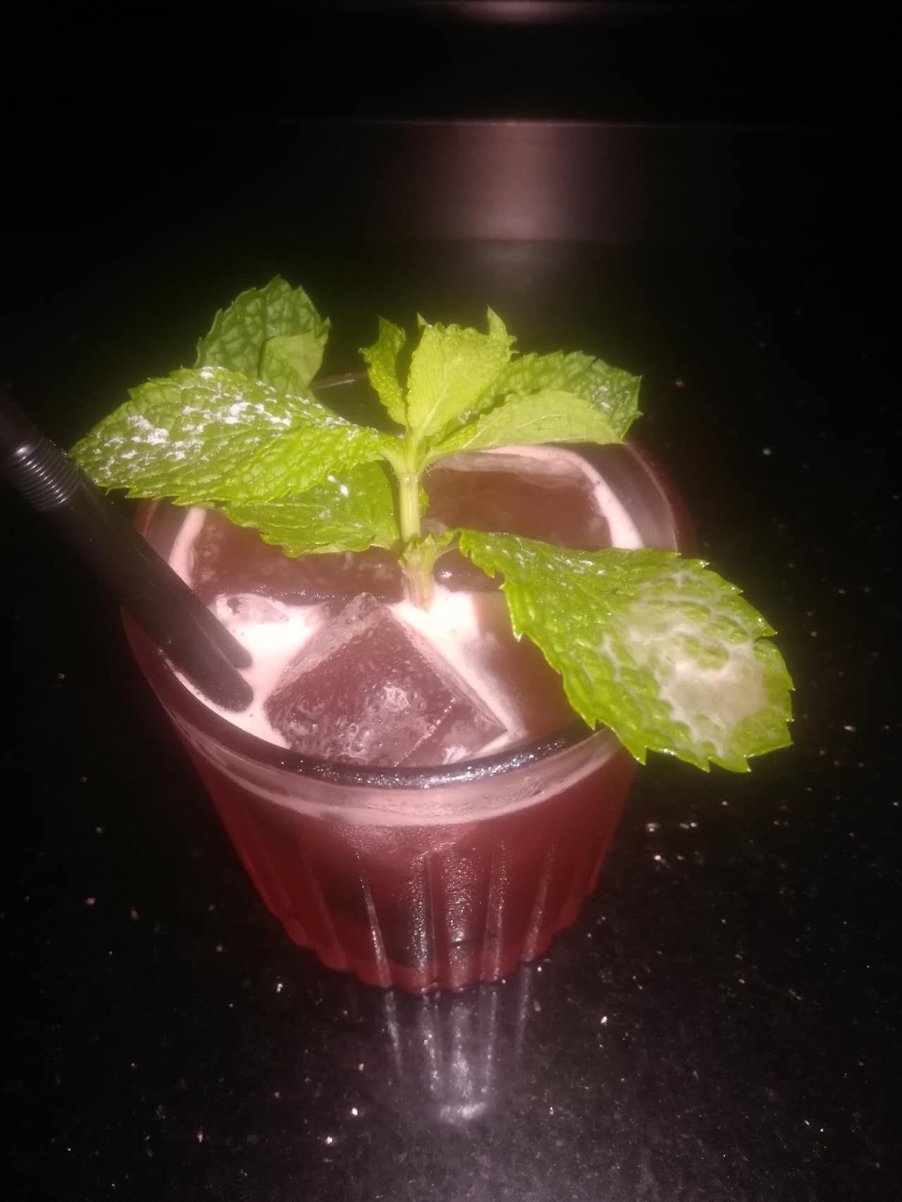 An iced red drink garnished with mint