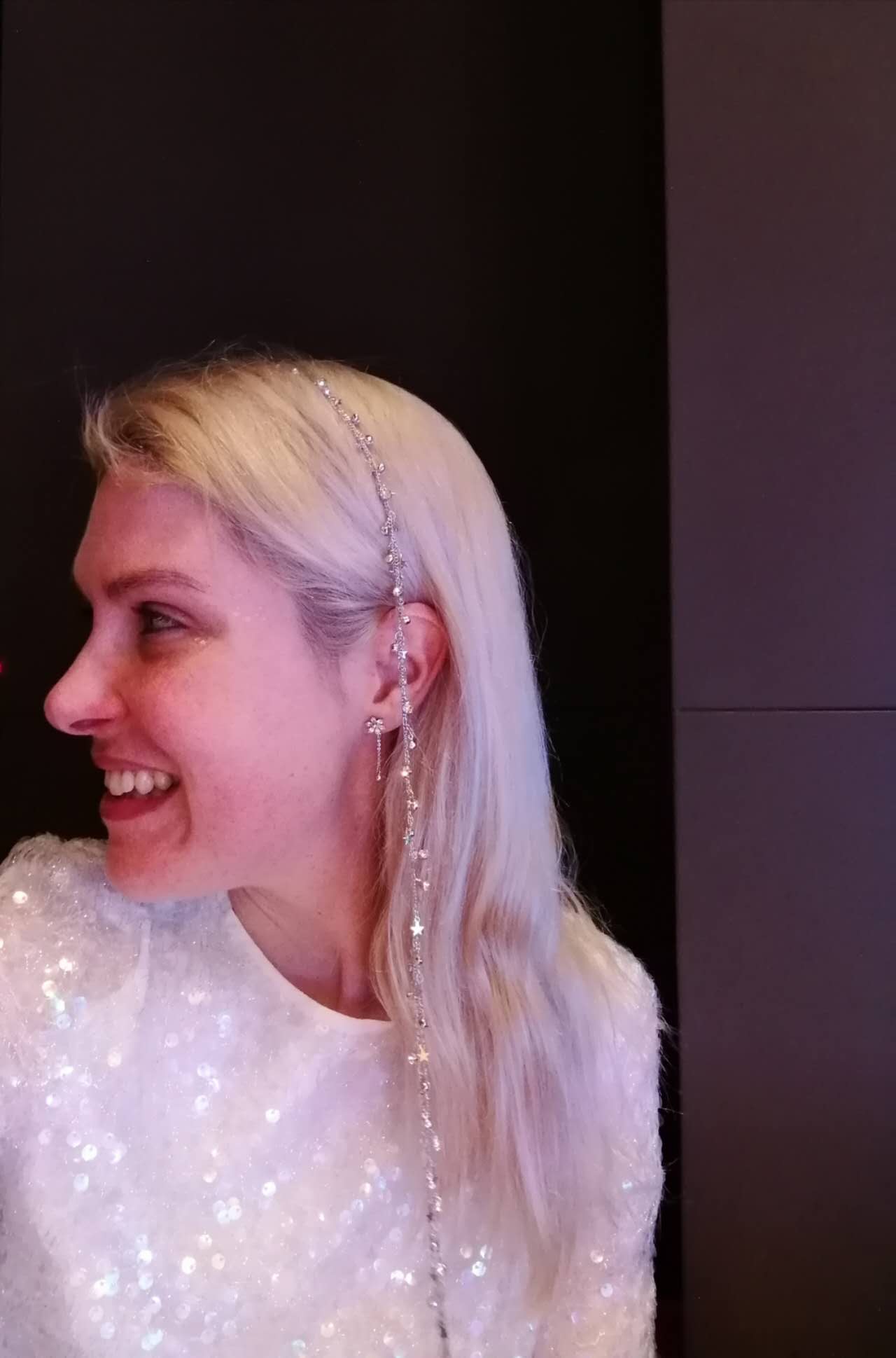 Rebecca smiling in a sequinned top with a decorative hair accessory