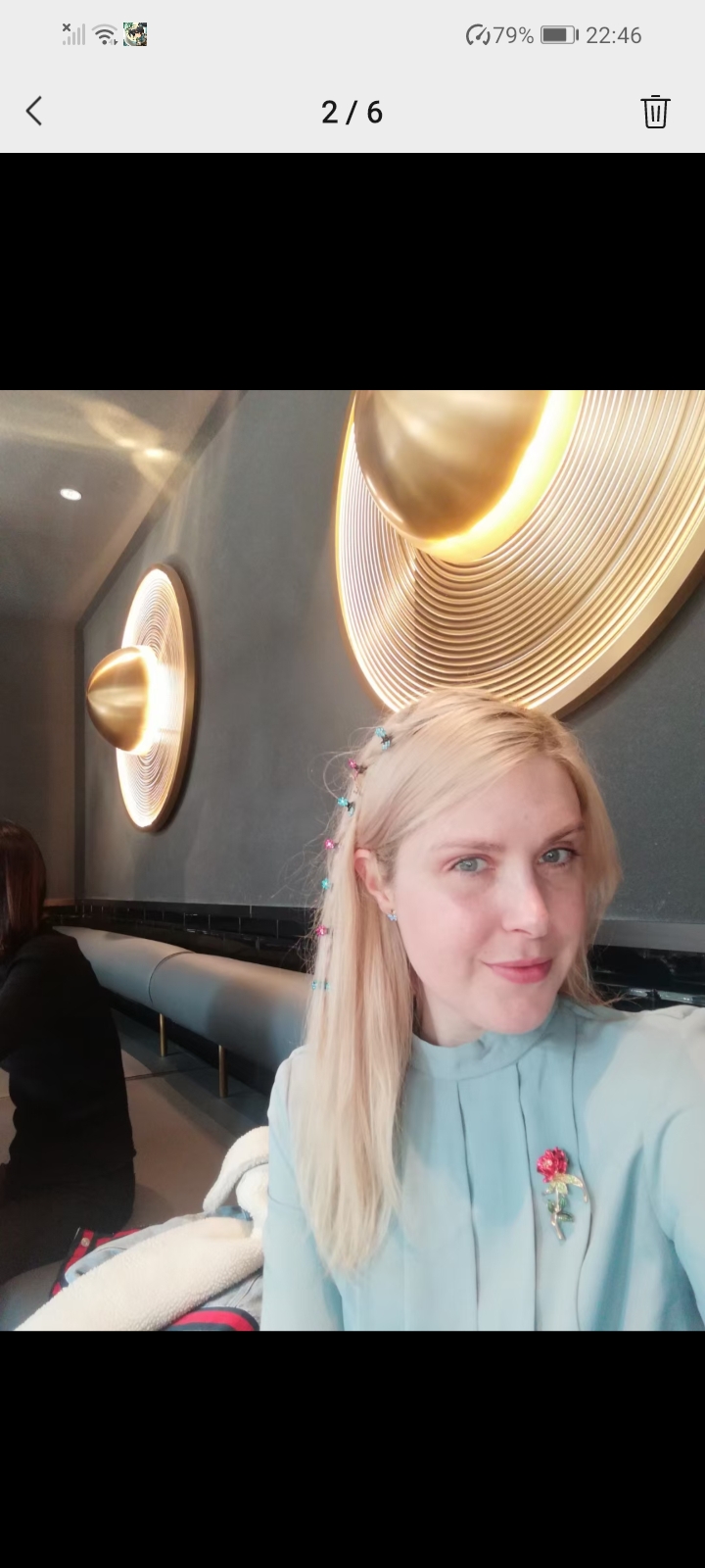 Rebecca seated beneath circular golden wall lights